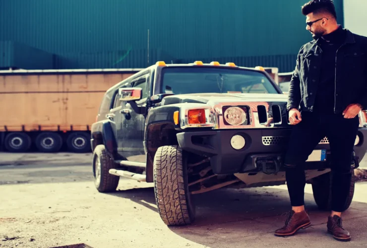 A rugged, masculine SUV driving off-road through a muddy terrain, showcasing its power and durability.